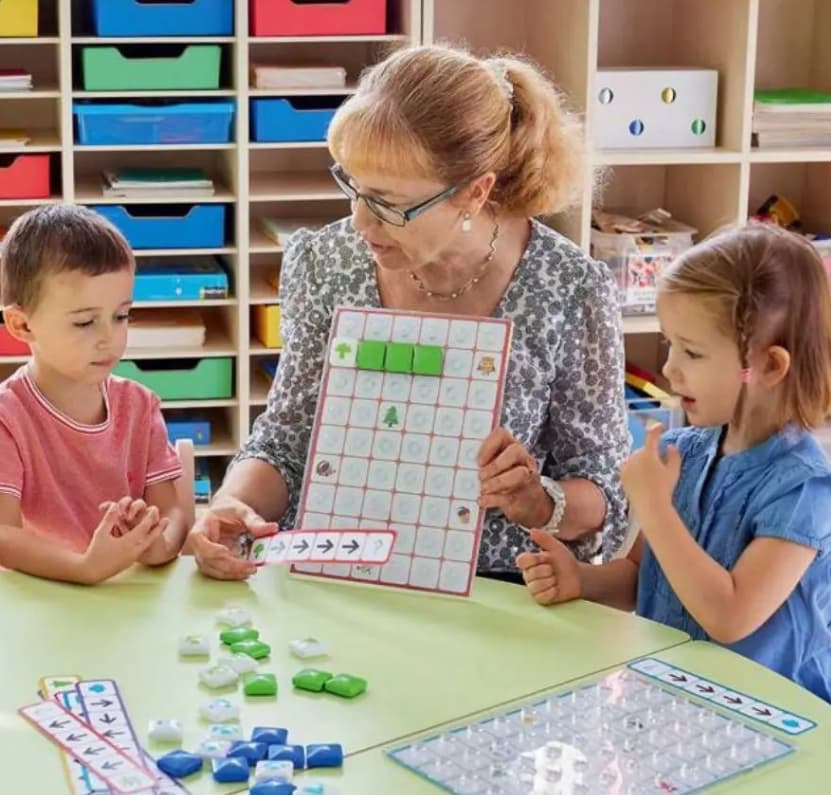 griglie per coding: insegnate al centro e due bambini ai lati che giocano e imparano