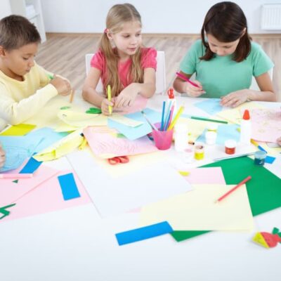 bambini che giocano/disegnano insieme radunati attorno ad un tavolo