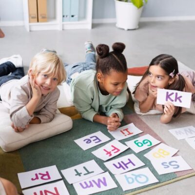 bambini che giocano con fogli ritraenti lettere in inglese